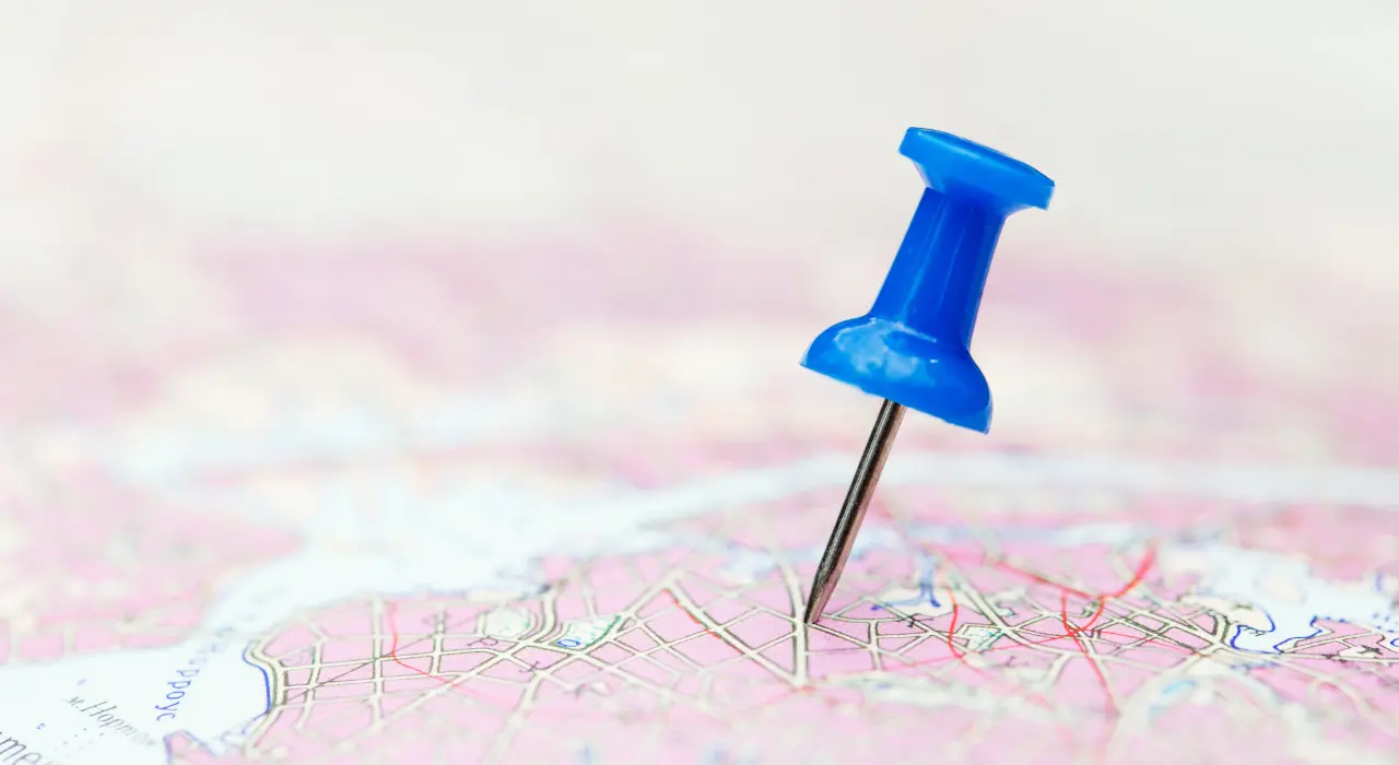 Un alfiler azul marca una ubicación específica en un mapa de papel.
