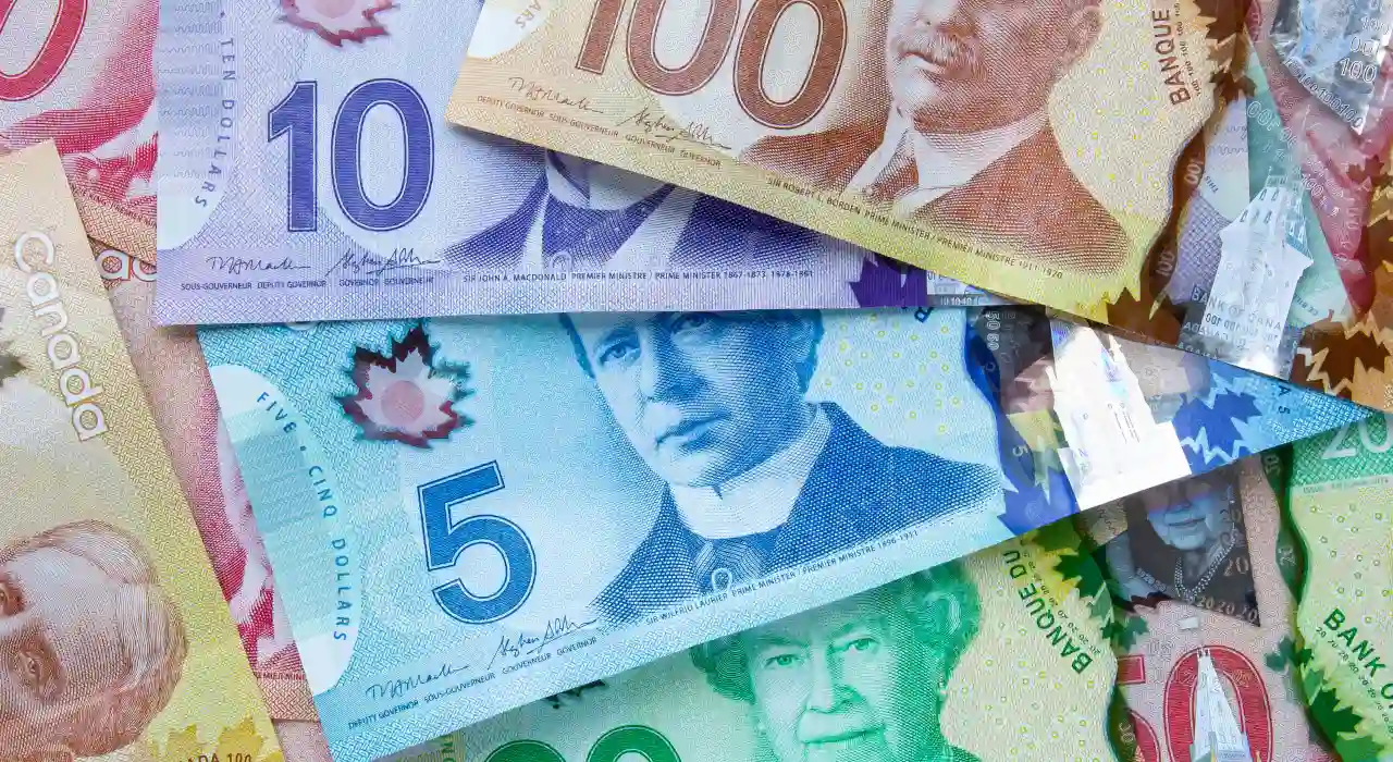 A pile of brightly coloured Canadian banknotes, including $5, $10, $20, $50, and $100 bills.