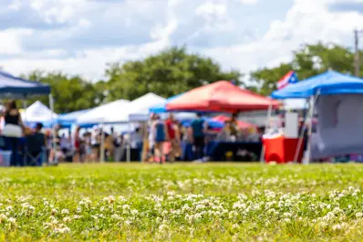 Outdoor community event with tents and people gathered on a sunny day