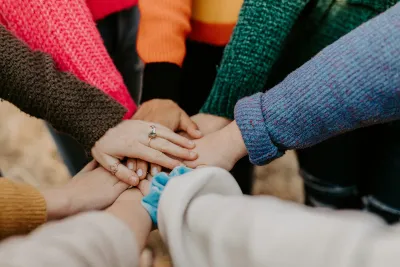 Group of people stacking hands in a gesture of teamwork